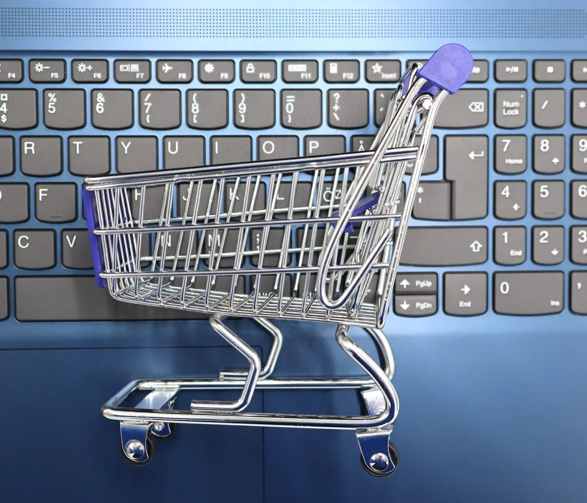 Carrinho de compras em miniatura sobre teclado de notebook