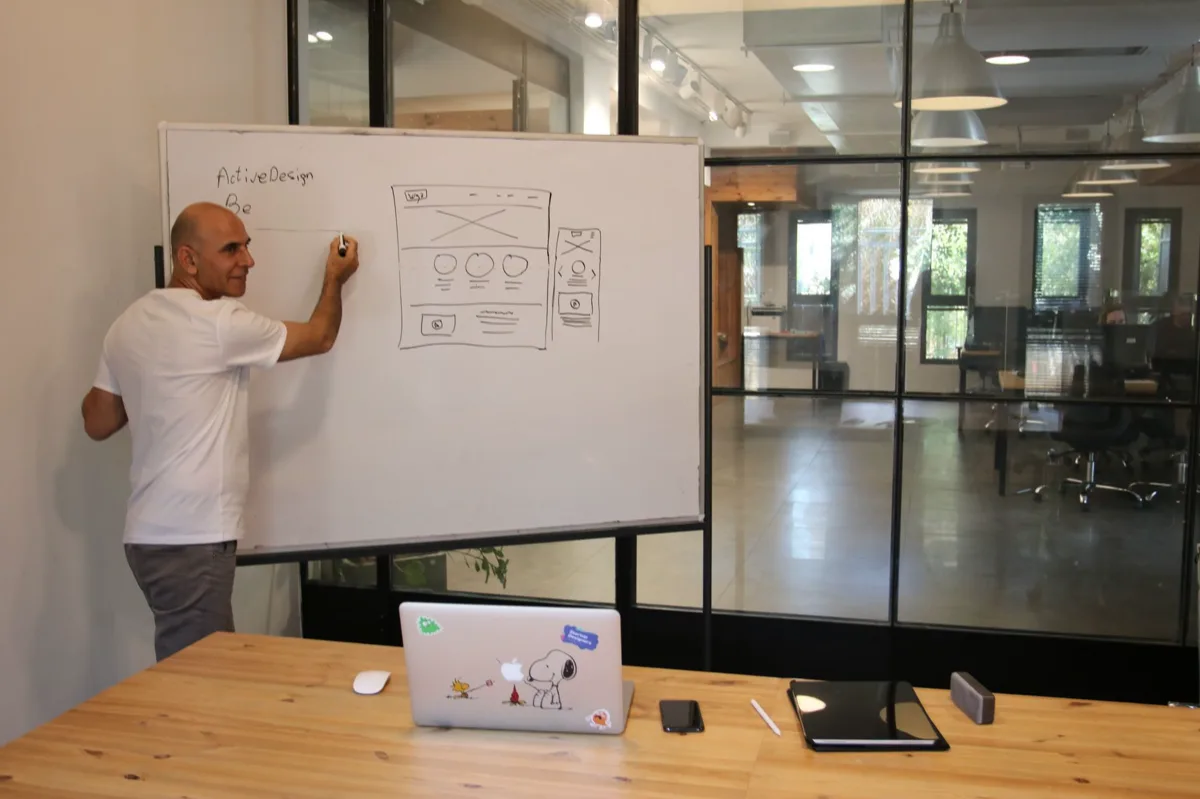 Designer esboçando jornada do usuário em ambiente colaborativo