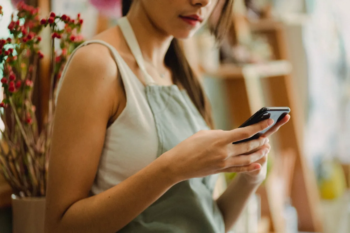 Dono de loja preocupado olhando para celular no balcão